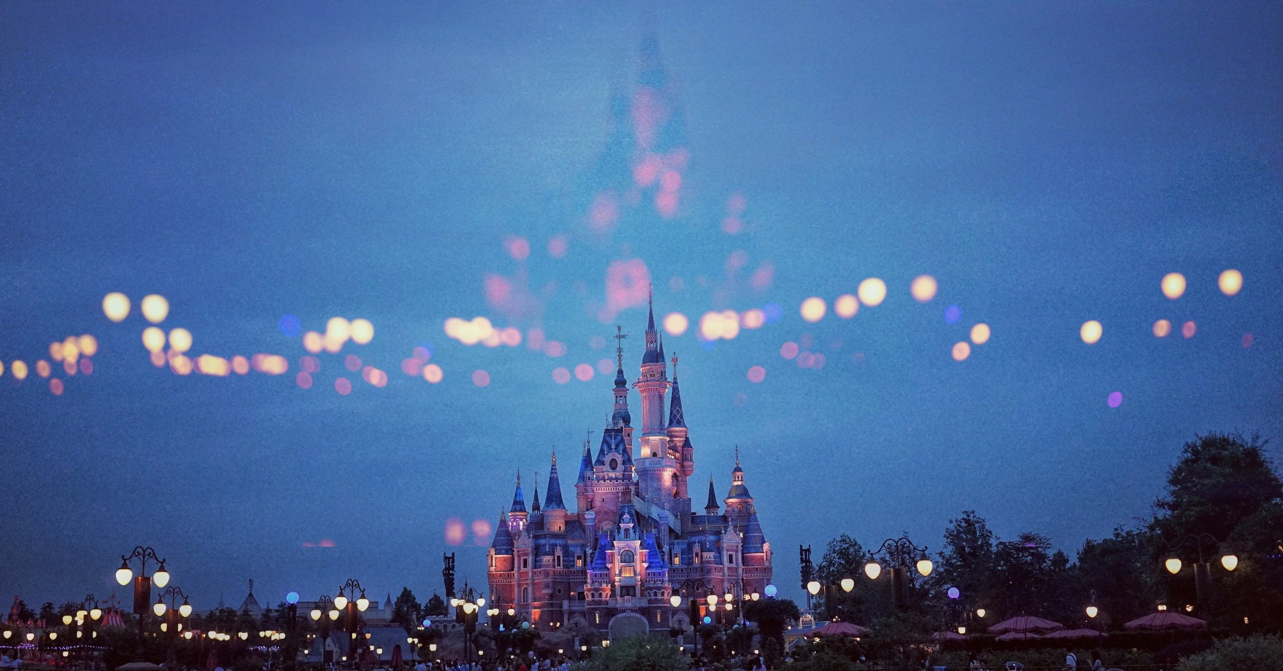 Castillo iluminado al anochecer en un parque de Disney